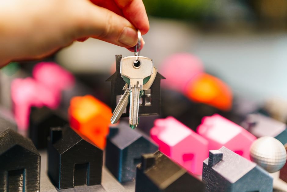 馬來西亞 Freehold Leasehold：Colorful miniature houses and a hand holding keys representi