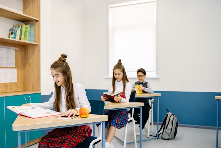 馬來西亞 國際學校 選體系：Three children studying at desks in a bright, modern classro